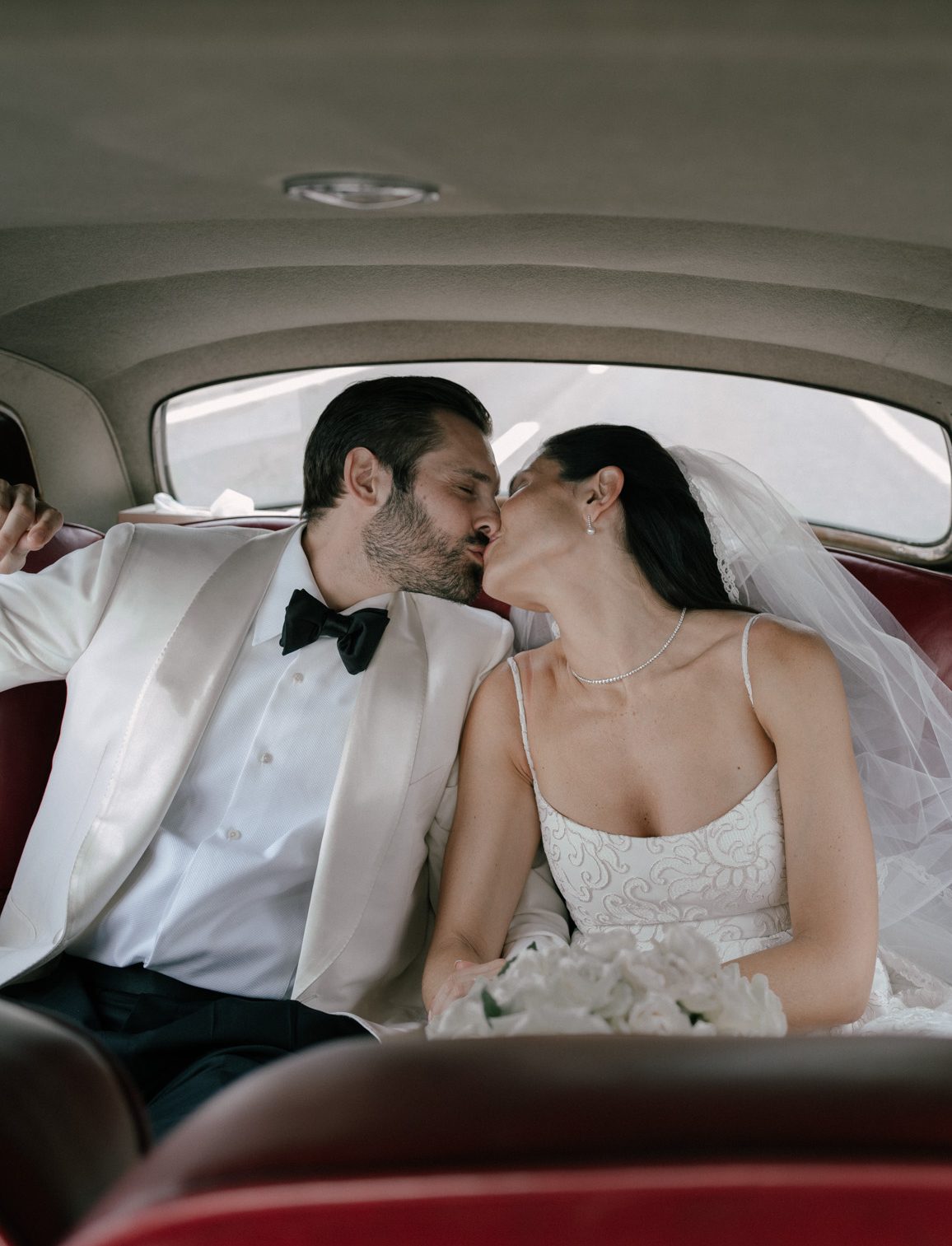 couple kissing in the back seat of a vintage vehicle captured by Philip White.