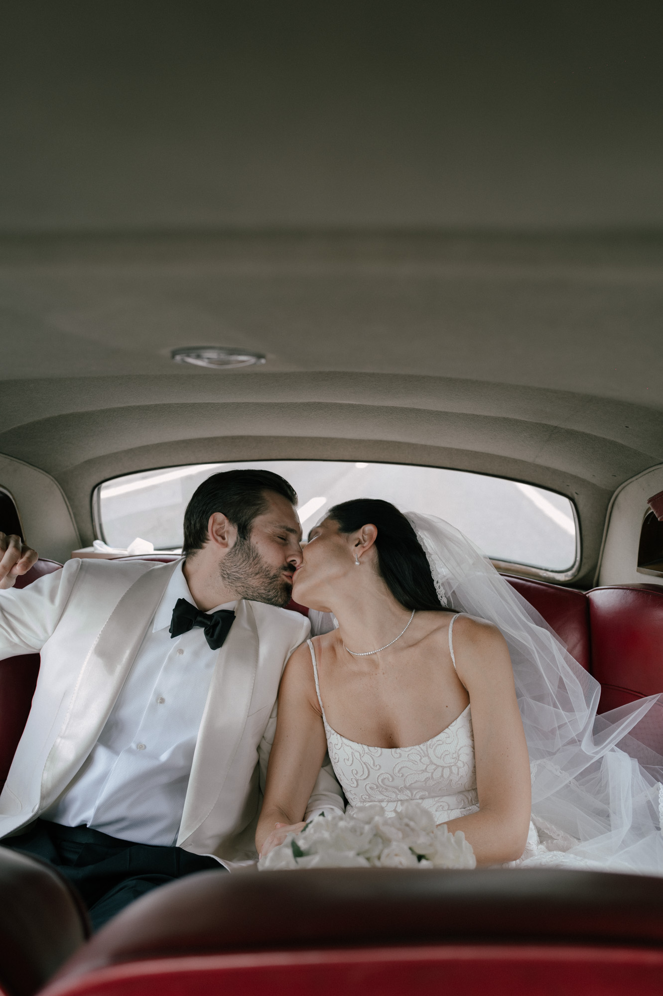 couple kissing in the back seat of a vintage vehicle.