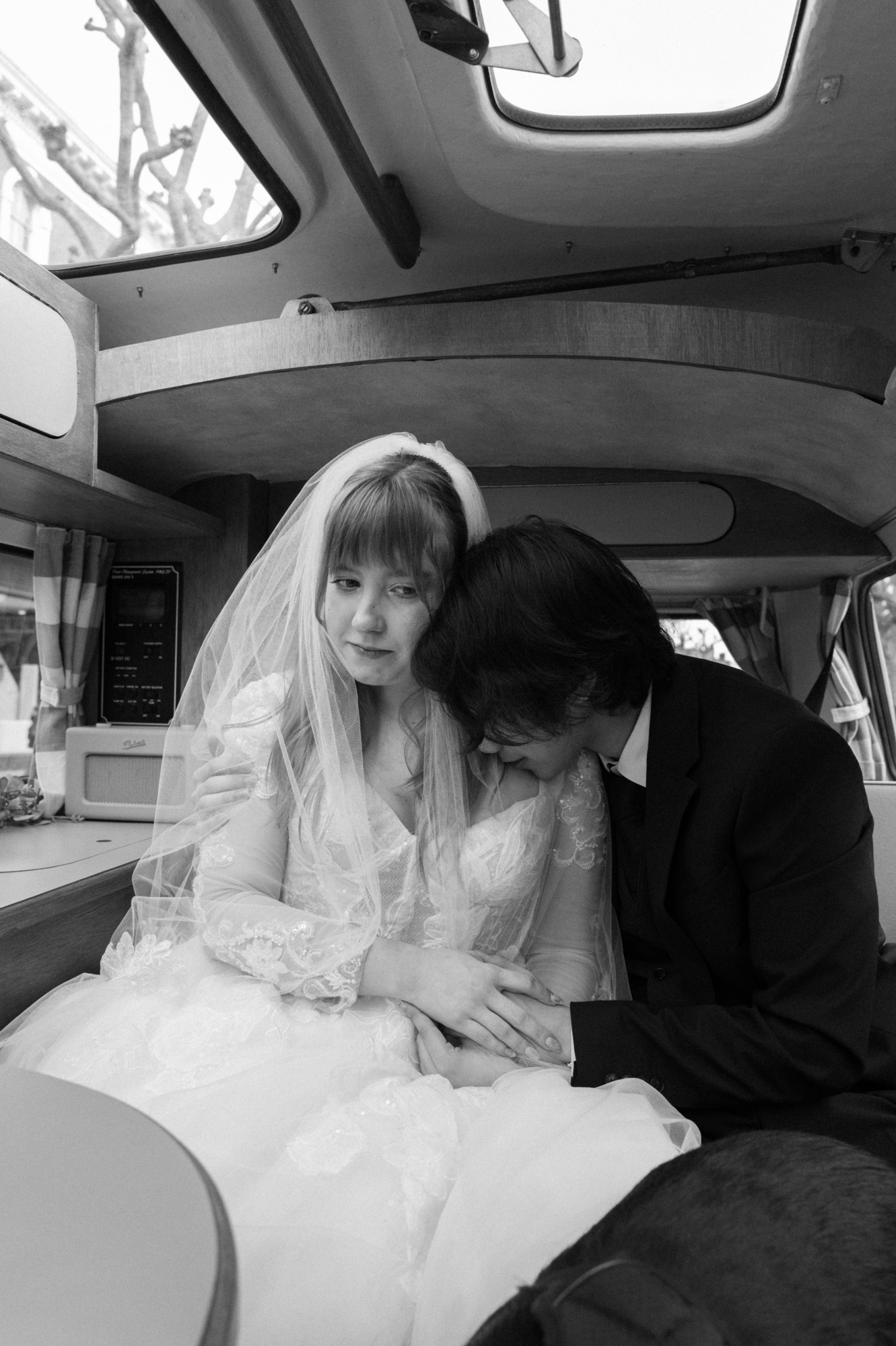 Young couple in a van on their wedding day in Fulham, with the groom resting his head on the bride’s shoulder as she looks pensively into the distance.