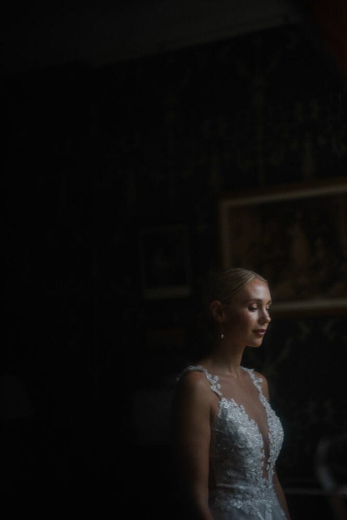 A bride is deep in reflection as she gazes out of the hotel window, taken by London Wedding Photographer Philip White.