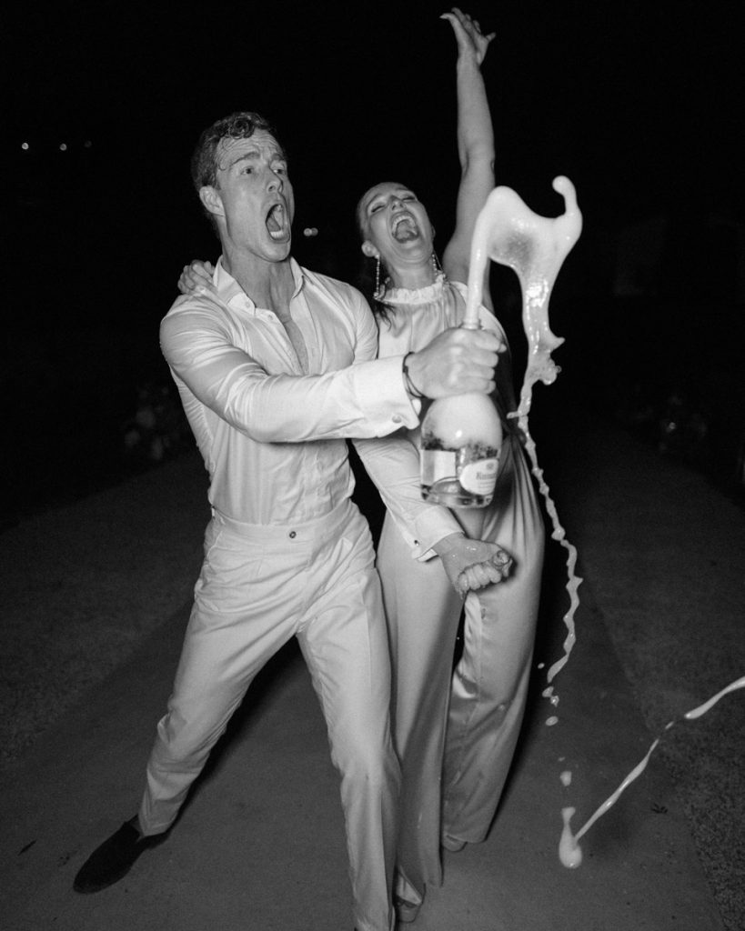 A joyous newly married couple pop a bottle of champagne open, taken by London Wedding Photographer Philip White.