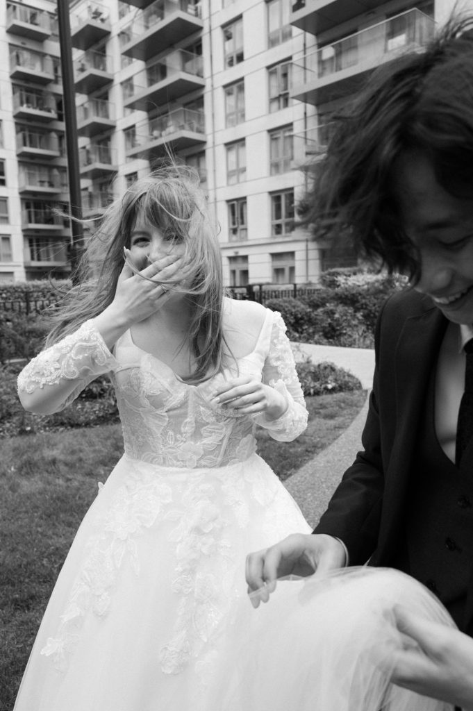 A bride laughs whilst holding her hand across her mouth, taken by London Wedding Photographer Philip White.