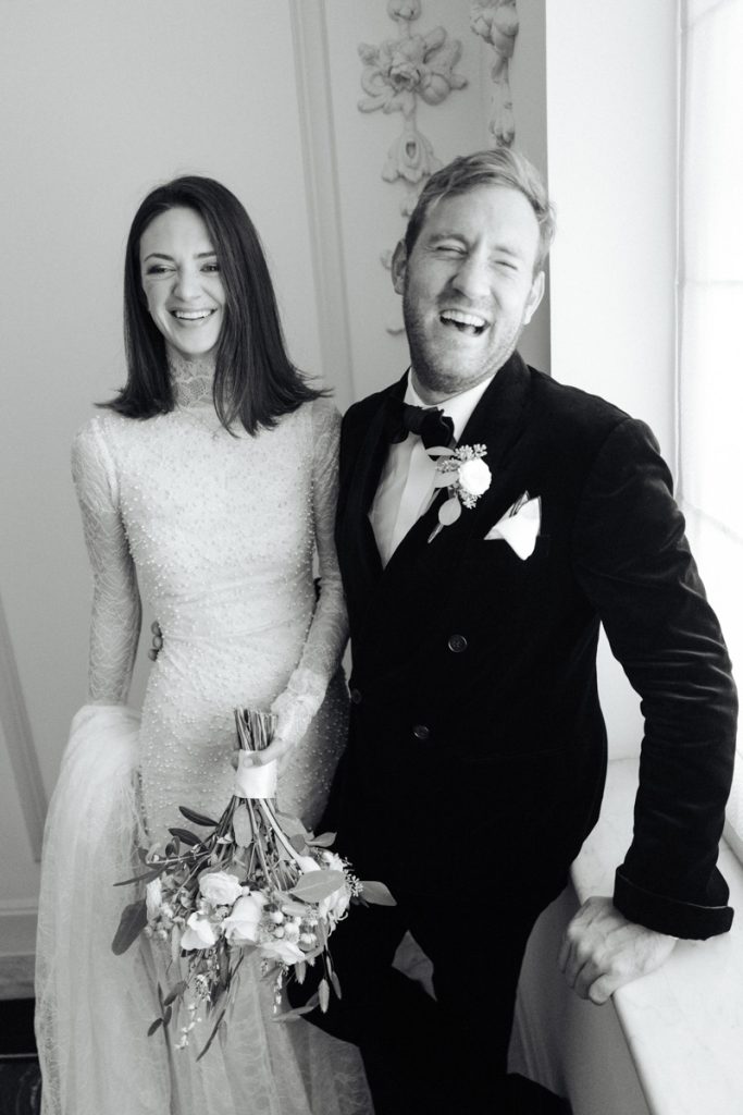 A newly married couple laugh together on a sofa captured by London wedding photographer Philip white.